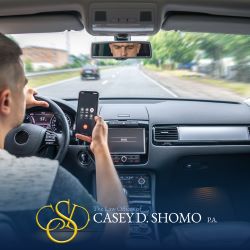 A distracted driver looks at their phone while behind the wheel in Palm Beach Gardens