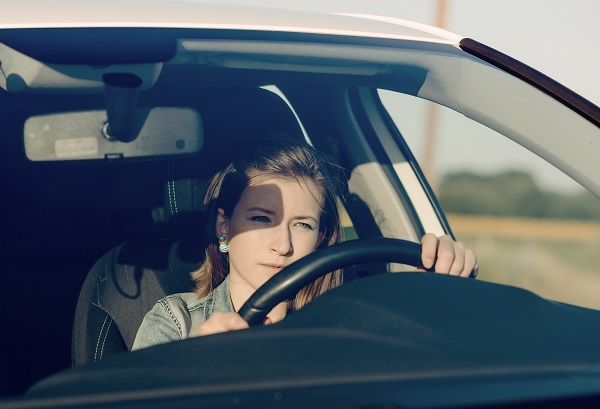 Teenage girl driving a car, holding the steering wheel with both hands and looking forward with a focused expression. (88409321)